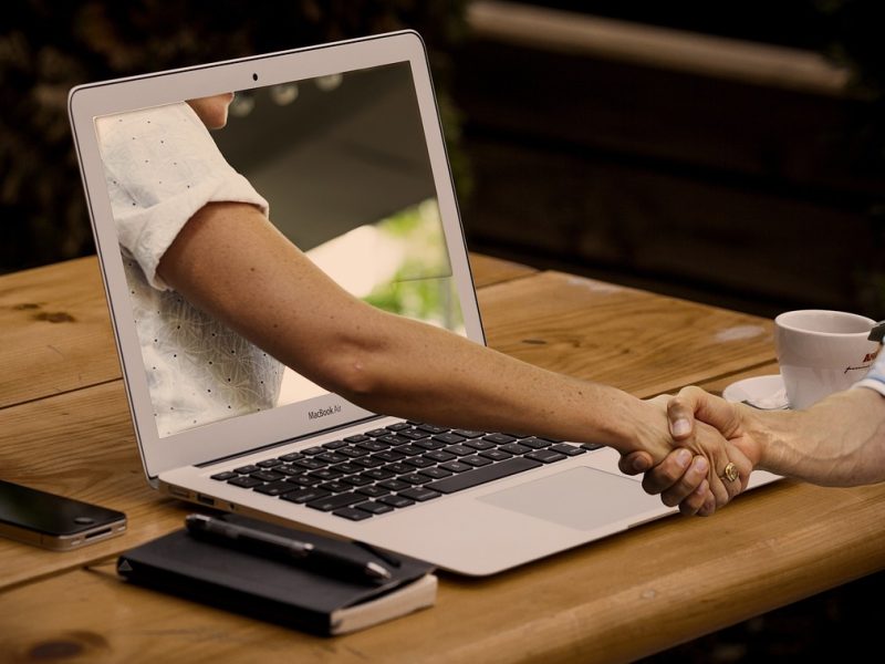 arm reaching out of the laptop to shake a hand